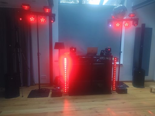 DJ-Pult mit roten Lichtern, Lautsprechern und einem modernen, stylischen Setup.